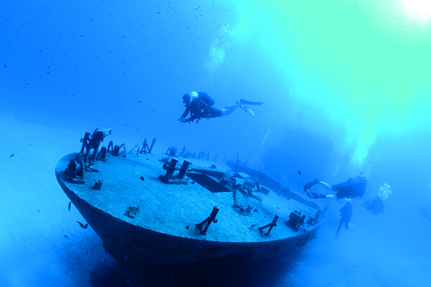 Plongeurs explorant l’épave du P-29, patrouilleur décommissionné et sabordé en 2009 à proximité de l’île de Comino (archipel de Malte/Méditerranée) sur un fond de sable, à - 20 mètres. 